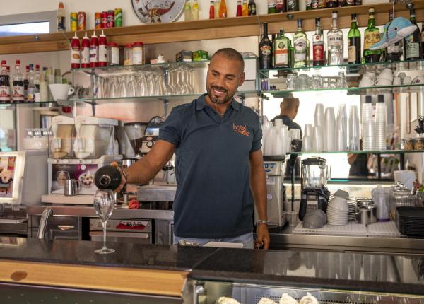 Bartender serves wine in a well-stocked bar.