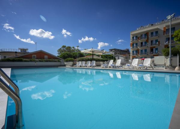 Piscina all'aperto con lettini e cielo sereno.